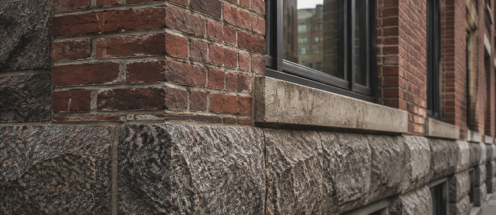 Weathered brick and granite base with repointed mortar joints and a limestone sill